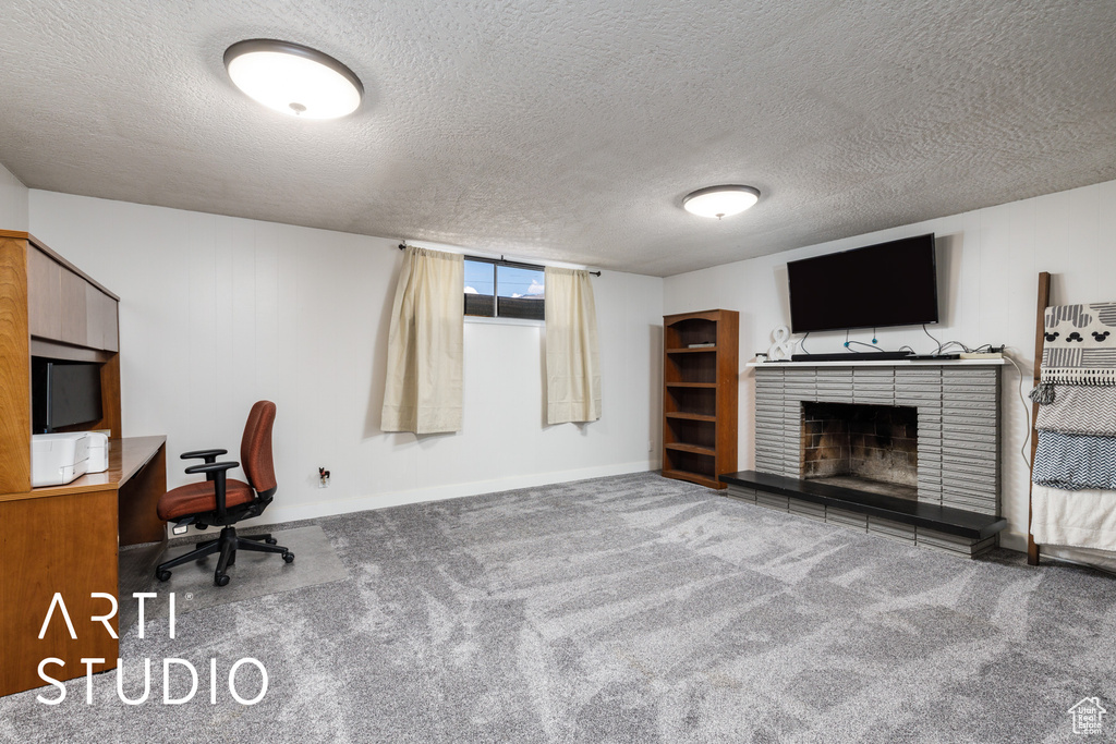 Carpeted office with baseboards, a brick fireplace, and a textured ceiling