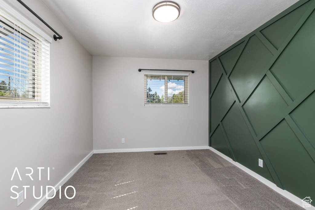 Empty room featuring baseboards, visible vents, and dark colored carpet