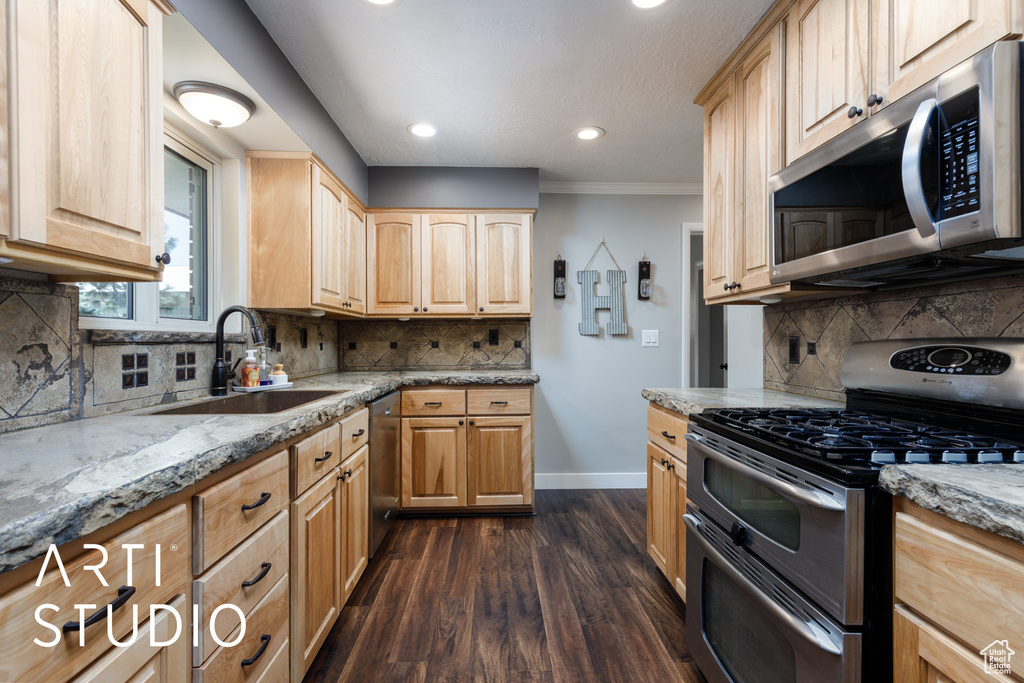 Kitchen with light brown cabinetry, stainless steel appliances, baseboards, and a sink