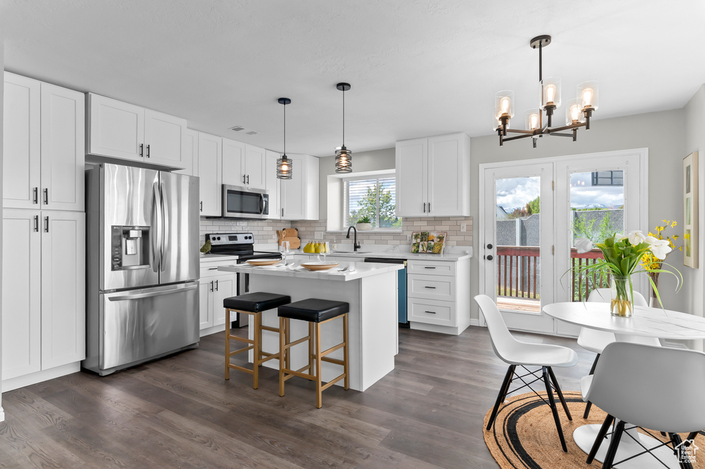 Kitchen with appliances with stainless steel finishes, tasteful backsplash, a sink, light countertops, and a chandelier
