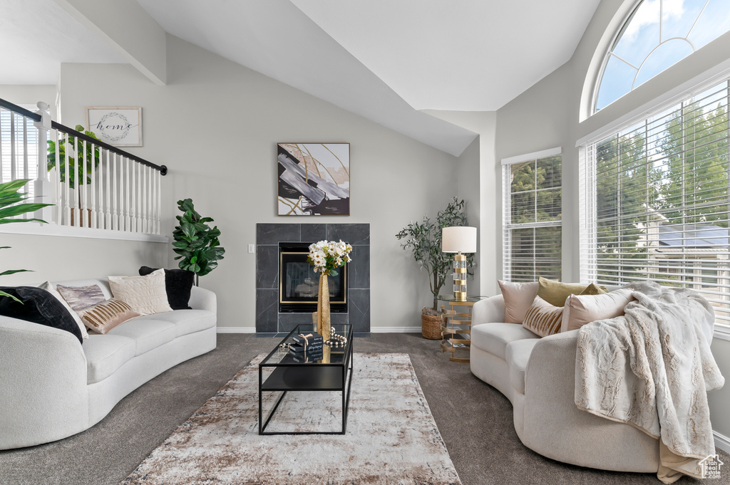 Living area featuring carpet floors, high vaulted ceiling, baseboards, and a tile fireplace