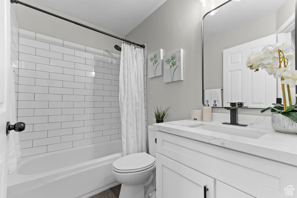 Bathroom with vanity, toilet, wood finished floors, and shower / tub combo with curtain