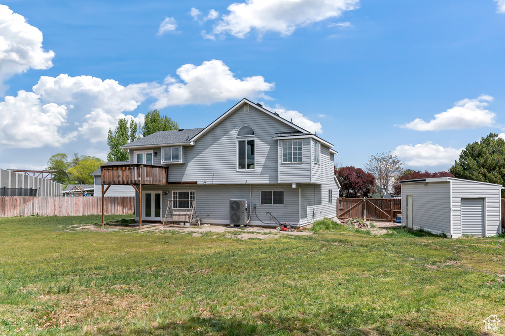 Back of property with a wooden deck, a fenced backyard, a patio area, french doors, and a lawn