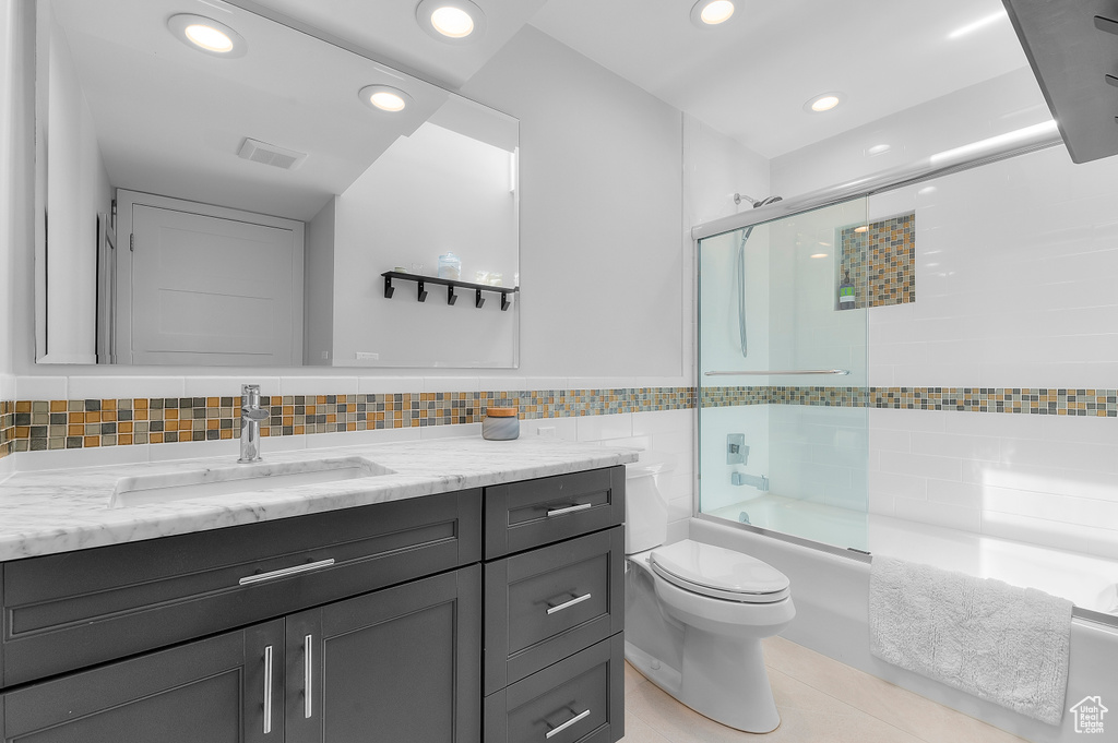 Bathroom with vanity, tile patterned flooring, toilet, recessed lighting, and combined bath / shower with glass door