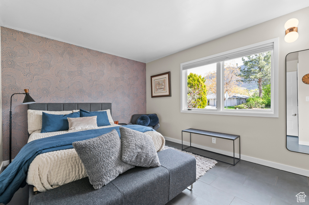Bedroom featuring wallpapered walls, multiple windows, baseboards, and an accent wall