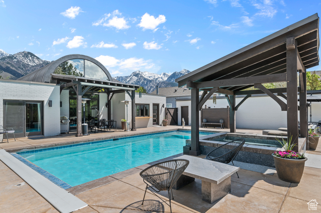 Outdoor pool featuring a gazebo, an in ground hot tub, a mountain view, and a patio