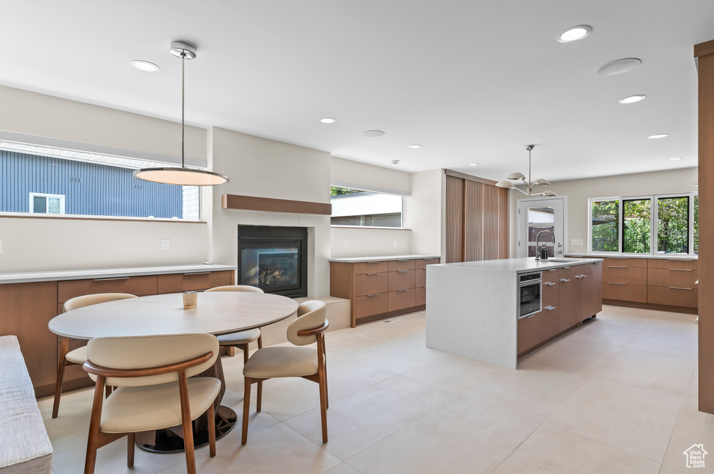 Kitchen with a glass covered fireplace, modern cabinets, brown cabinetry, and a sink
