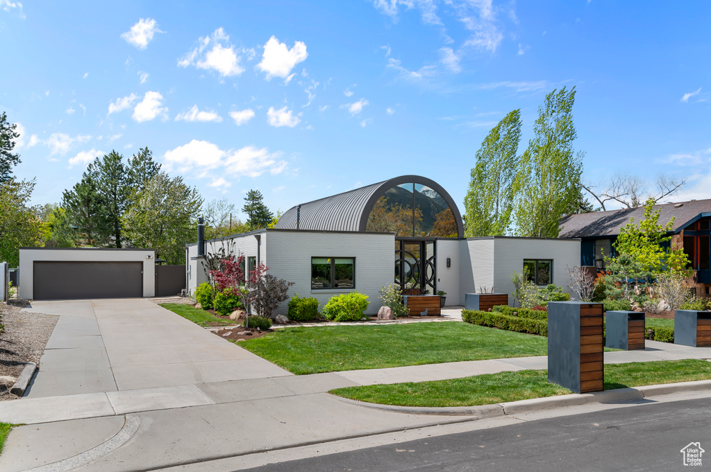 Contemporary home with a garage, concrete driveway, and a front yard