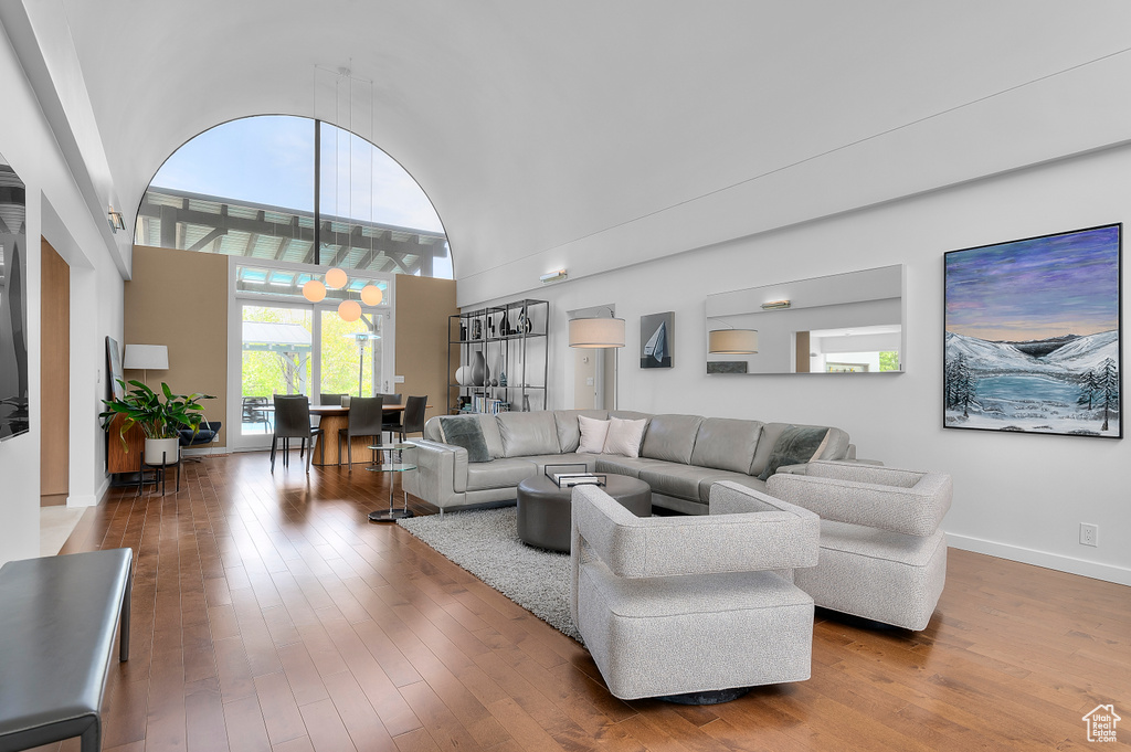 Living area featuring baseboards, wood-type flooring, and a towering ceiling