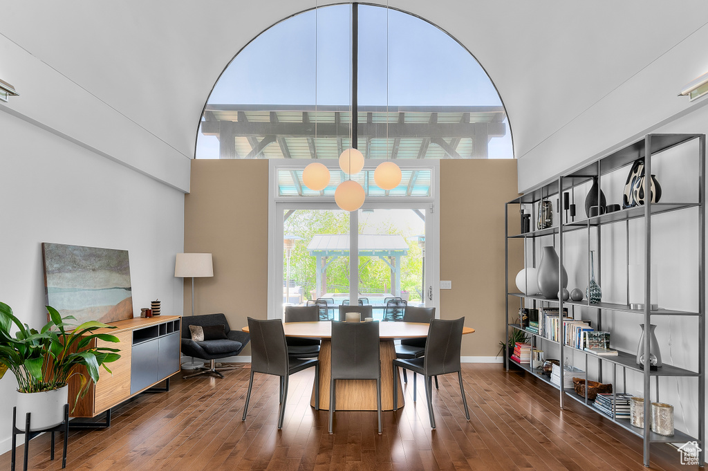Dining space featuring baseboards, a high ceiling, and wood finished floors