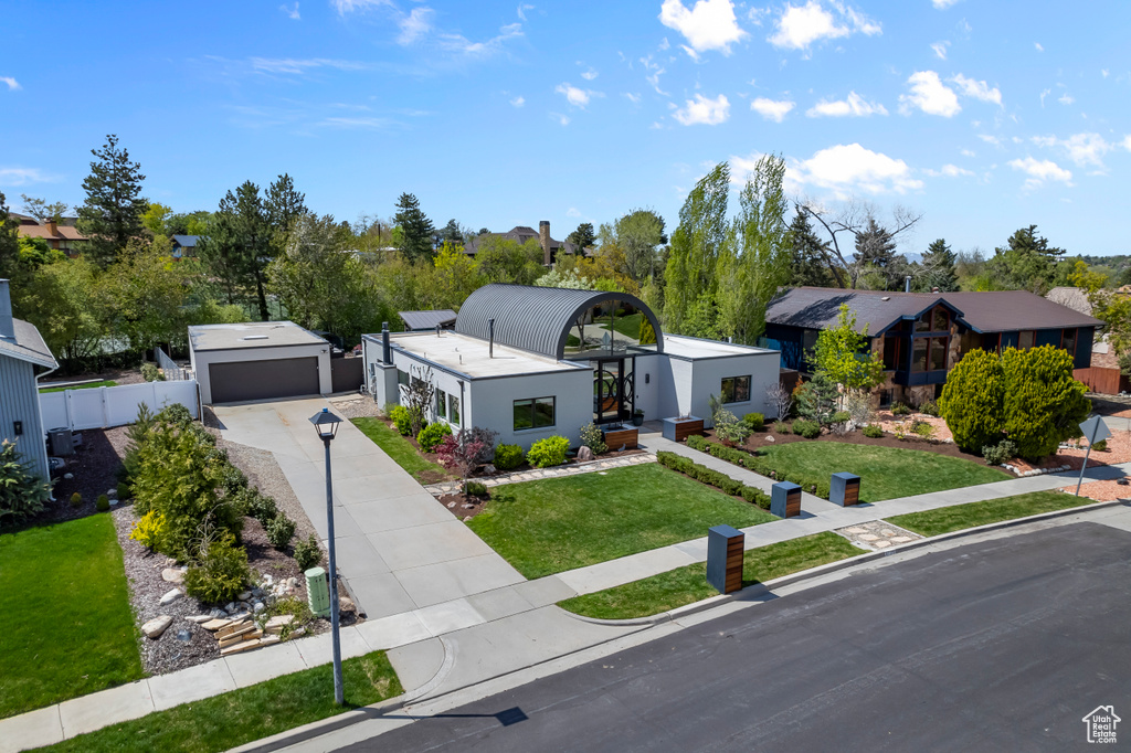 View of front of property with concrete driveway, fence, a front yard, and a garage