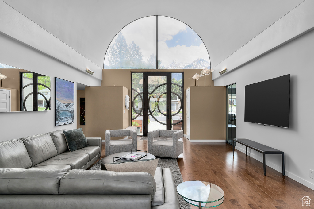 Living room featuring baseboards, a towering ceiling, wood finished floors, and a healthy amount of sunlight