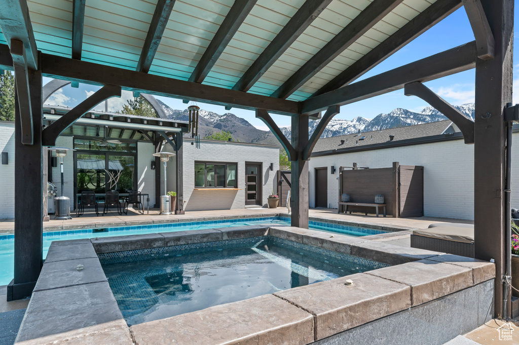 Pool with a mountain view, an in ground hot tub, and a patio