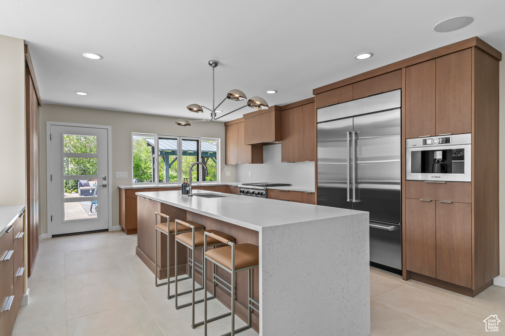 Kitchen featuring a sink, light countertops, recessed lighting, stainless steel built in fridge, and modern cabinets