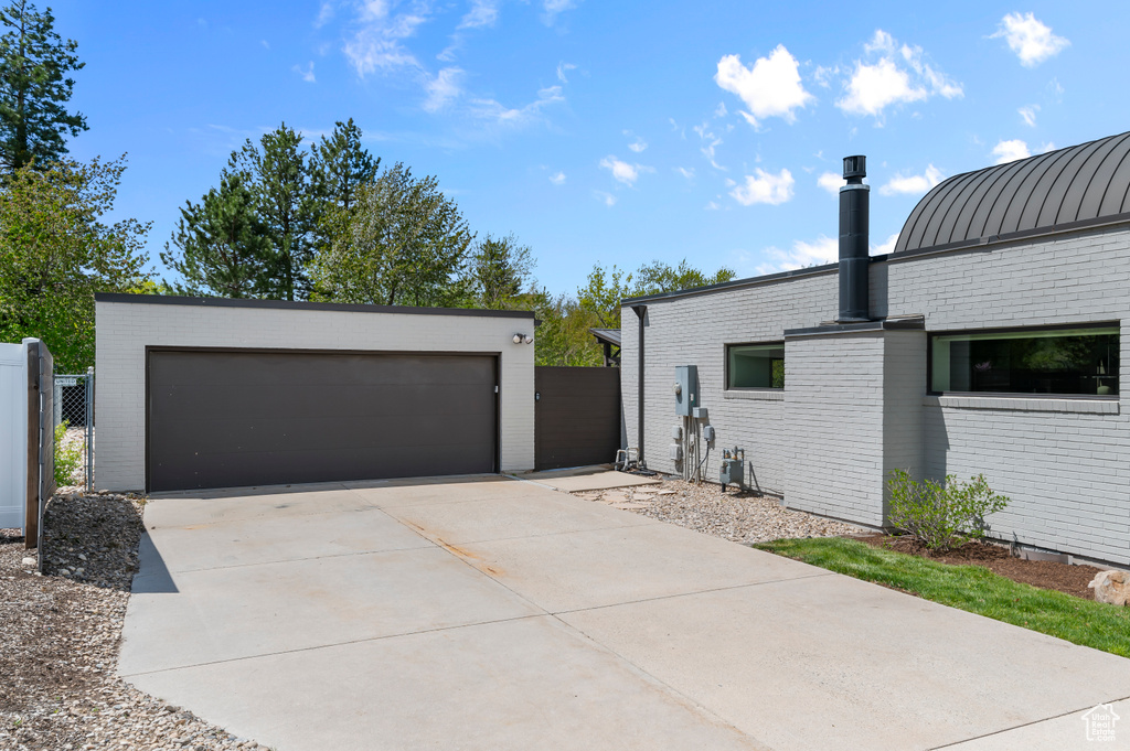 View of side of home with brick siding, fence, an outbuilding, and a standing seam roof