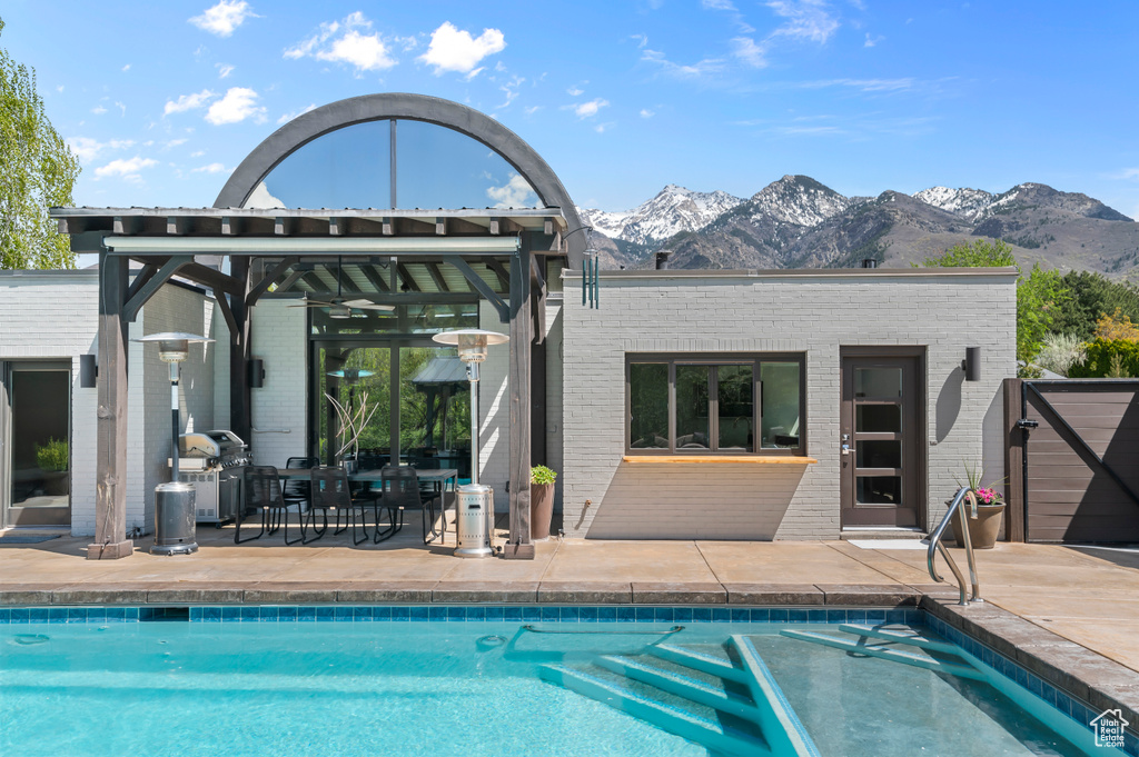 Back of house featuring brick siding, a mountain view, a patio area, and an outdoor pool