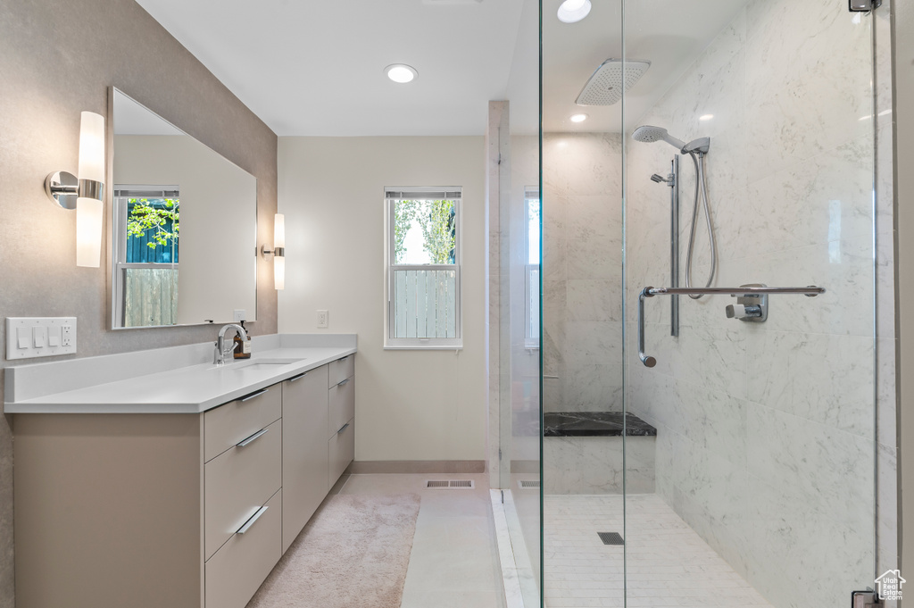 Bathroom featuring baseboards, a walk in shower, visible vents, and vanity