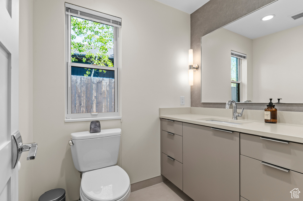 Half bathroom featuring vanity, baseboards, toilet, and visible vents