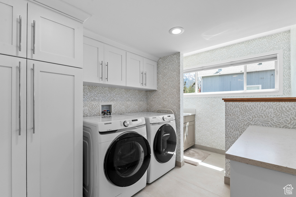 Laundry area featuring cabinet space, separate washer and dryer, and wallpapered walls