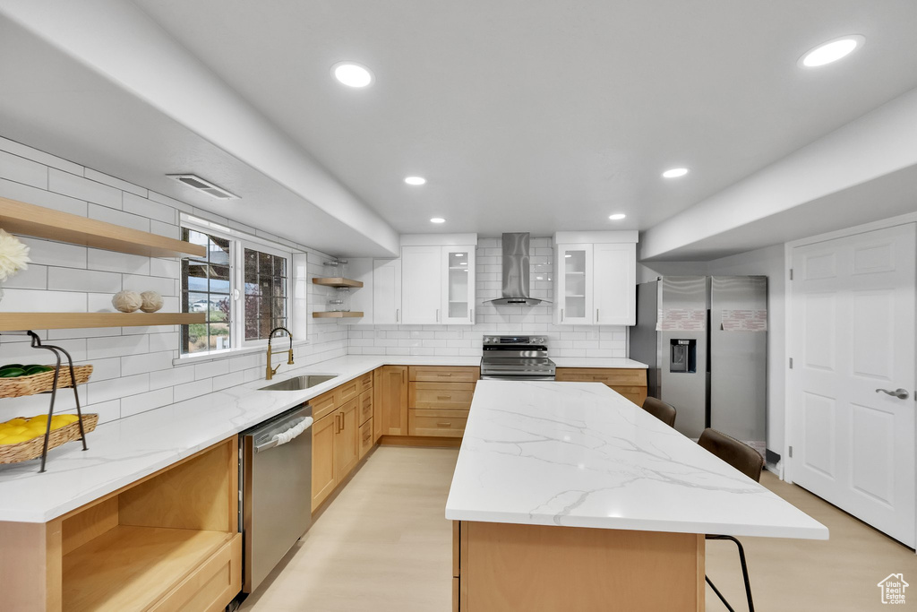 Kitchen featuring wall chimney range hood, open shelves, appliances with stainless steel finishes, a sink, and visible vents