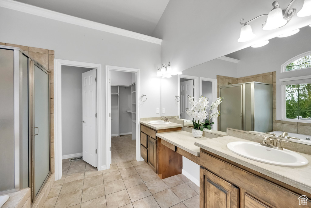 Full bathroom featuring a sink, a walk in closet, double vanity, tile patterned floors, and a shower stall
