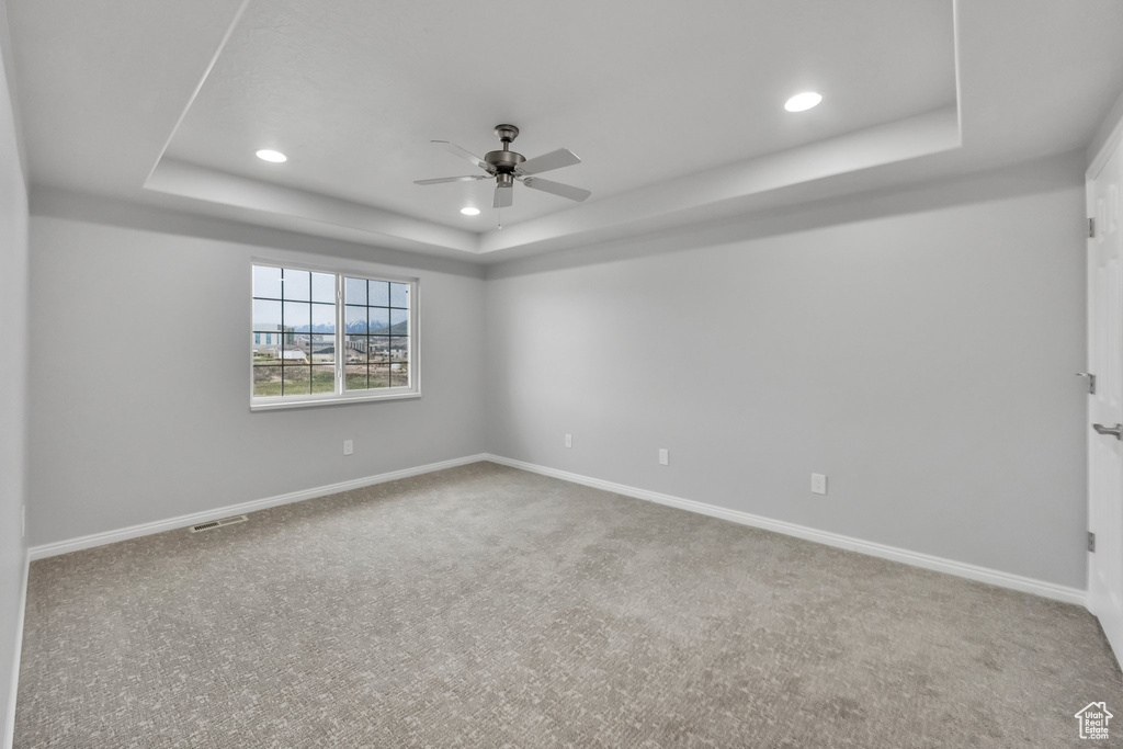 Spare room with carpet, a ceiling fan, recessed lighting, a tray ceiling, and visible vents