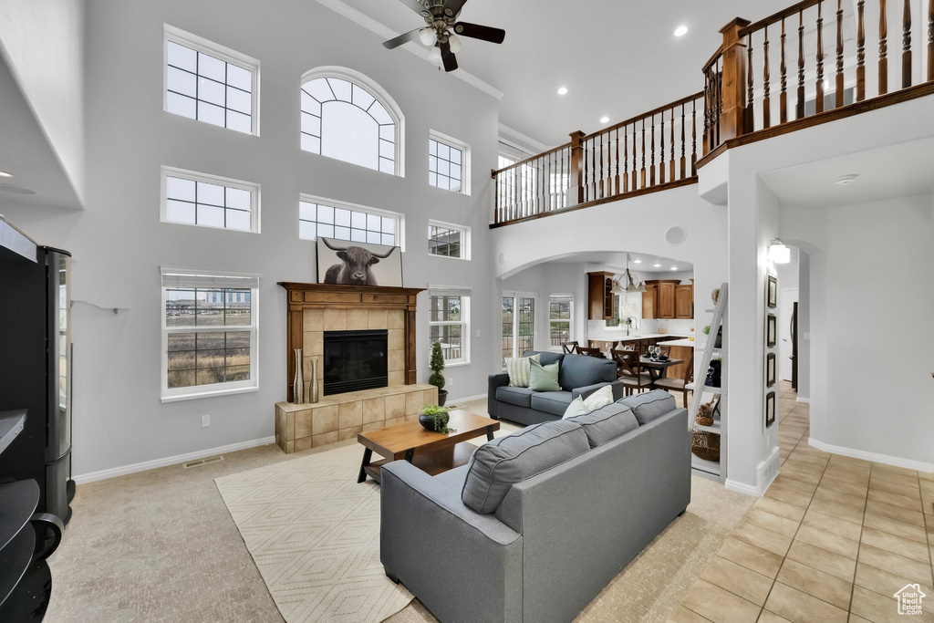 Living area with ceiling fan, arched walkways, a fireplace, baseboards, and a high ceiling