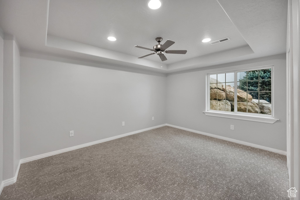 Unfurnished room with ceiling fan, carpet, a tray ceiling, and visible vents