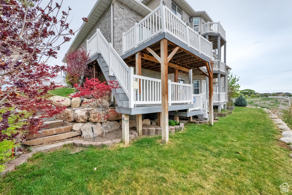 View of home's exterior featuring a lawn, stairway, and a deck