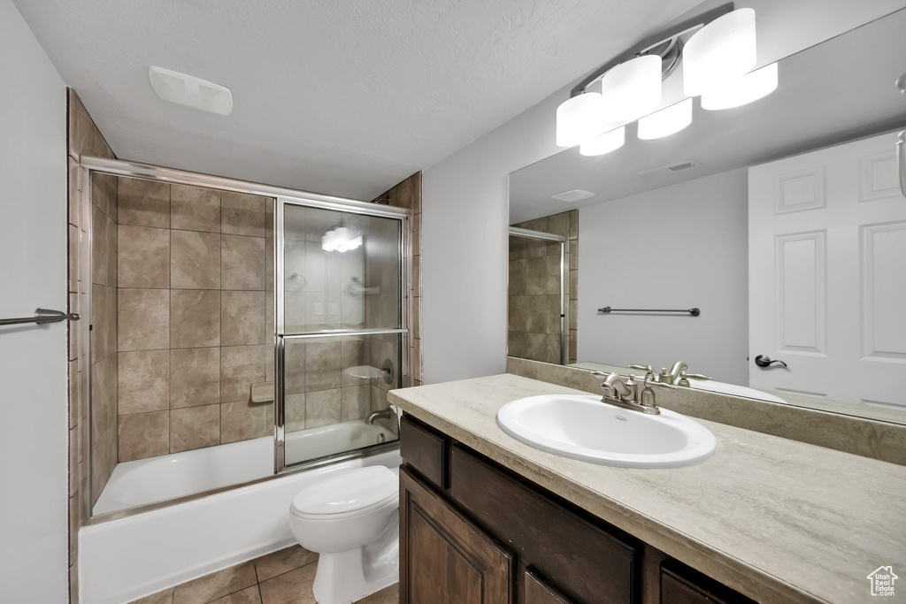 Bathroom with vanity, visible vents, toilet, tile patterned floors, and enclosed tub / shower combo