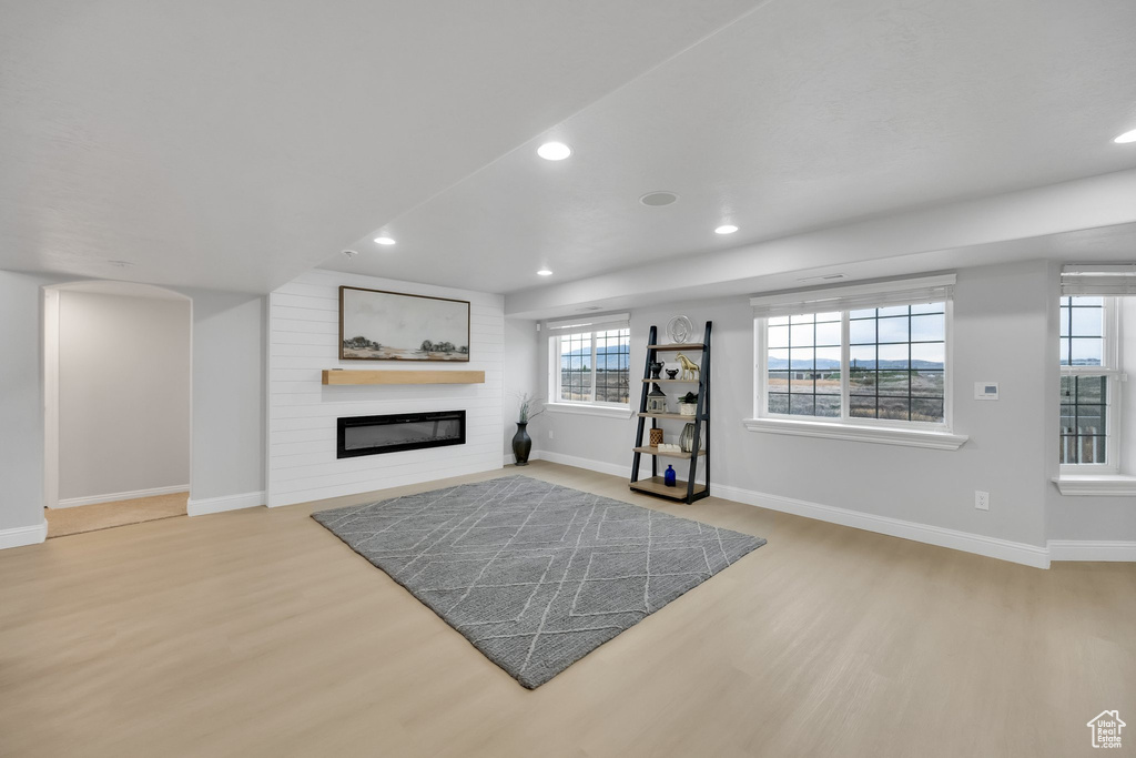 Unfurnished living room featuring baseboards, recessed lighting, wood finished floors, and a fireplace