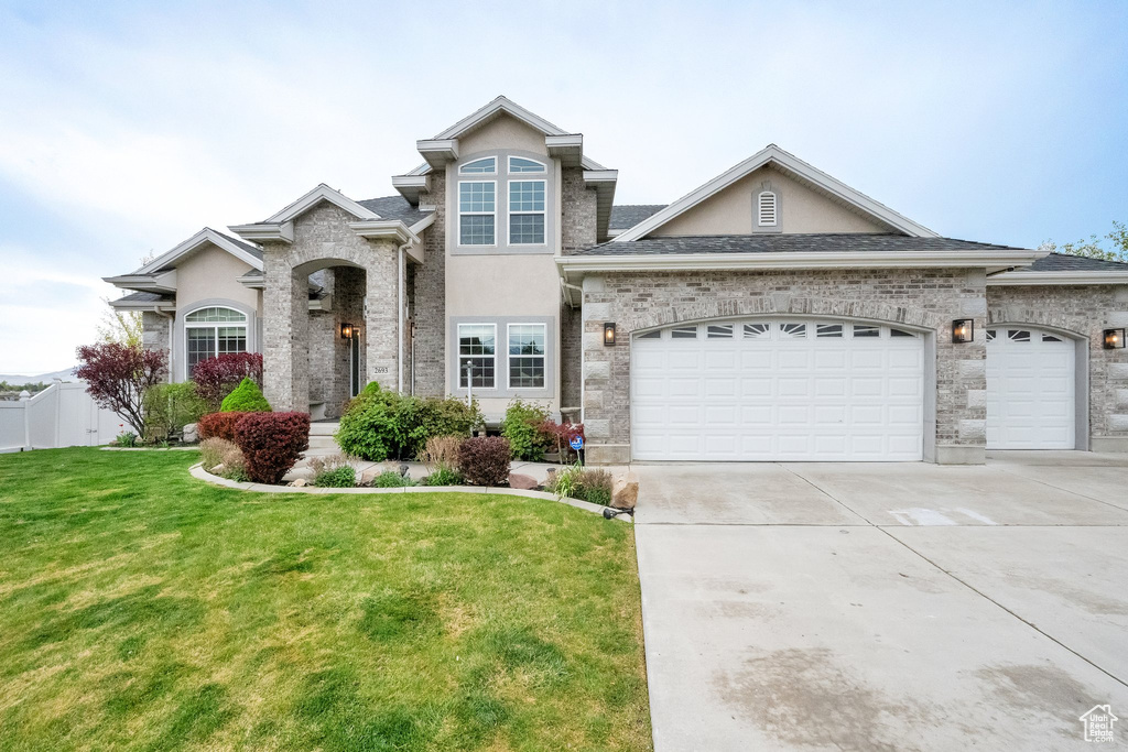 View of front of house with a garage, stucco siding, concrete driveway, and a front yard