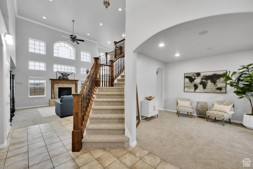 Stairs with a ceiling fan, a fireplace, baseboards, arched walkways, and carpet