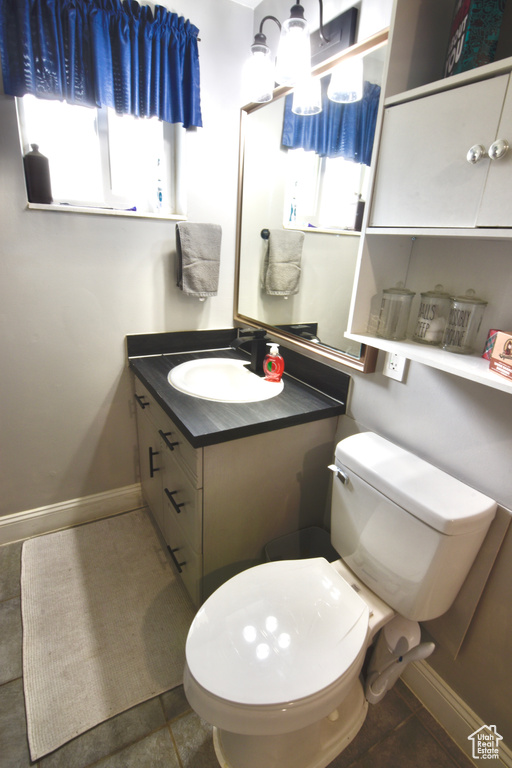 Bathroom featuring vanity, toilet, and baseboards