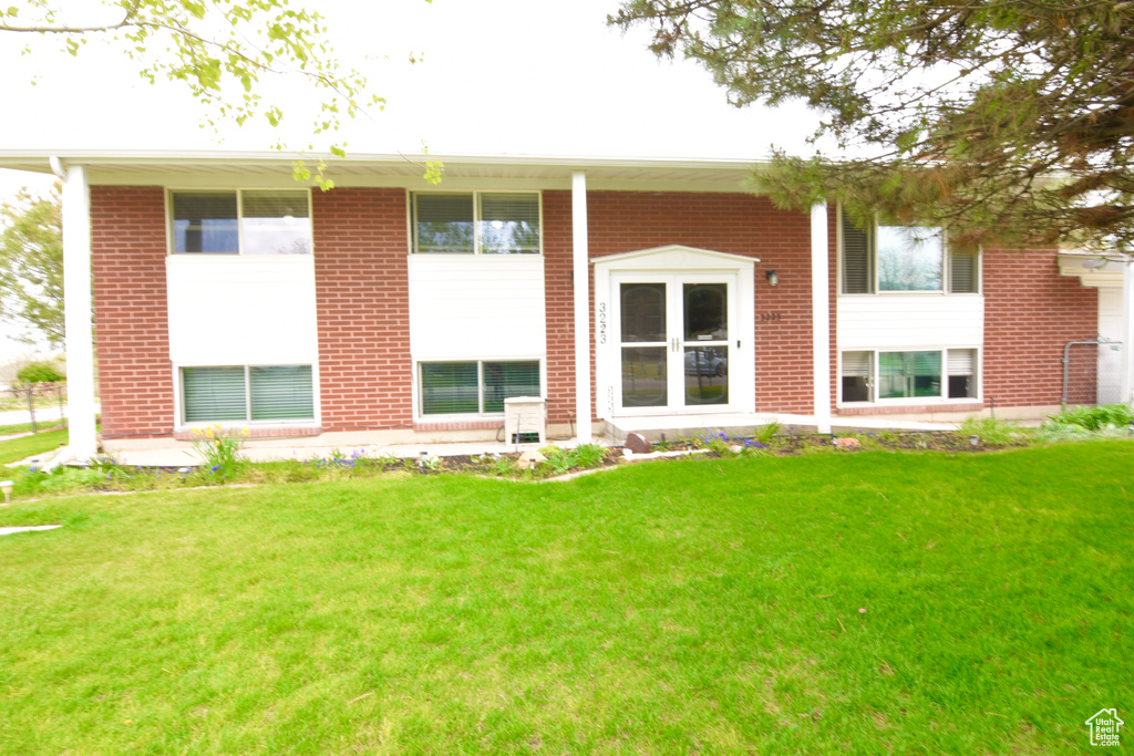 Rear view of house with a yard and brick siding
