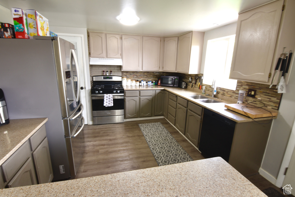 Kitchen with appliances with stainless steel finishes, a sink, tasteful backsplash, and under cabinet range hood