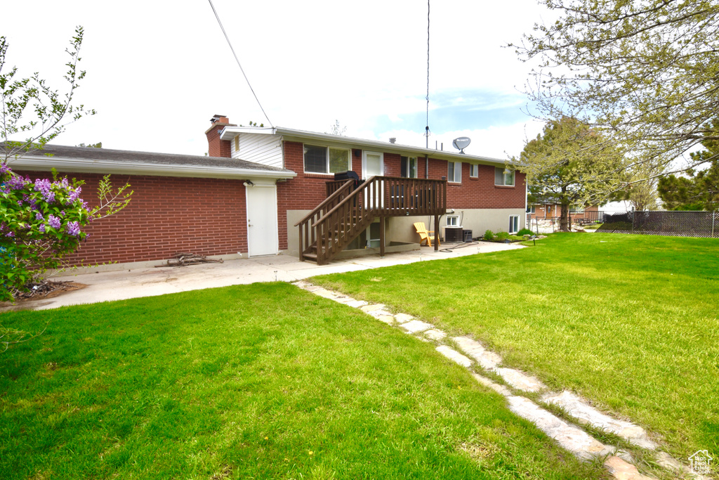 Rear view of house featuring a chimney, a patio area, fence, a yard, and brick siding