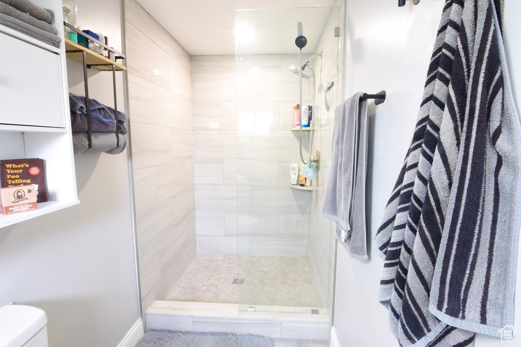 Bathroom with a tile shower, toilet, and baseboards