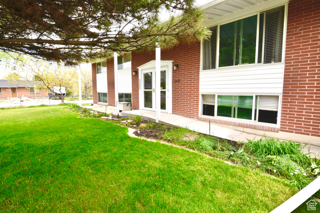 View of property exterior featuring a yard and brick siding