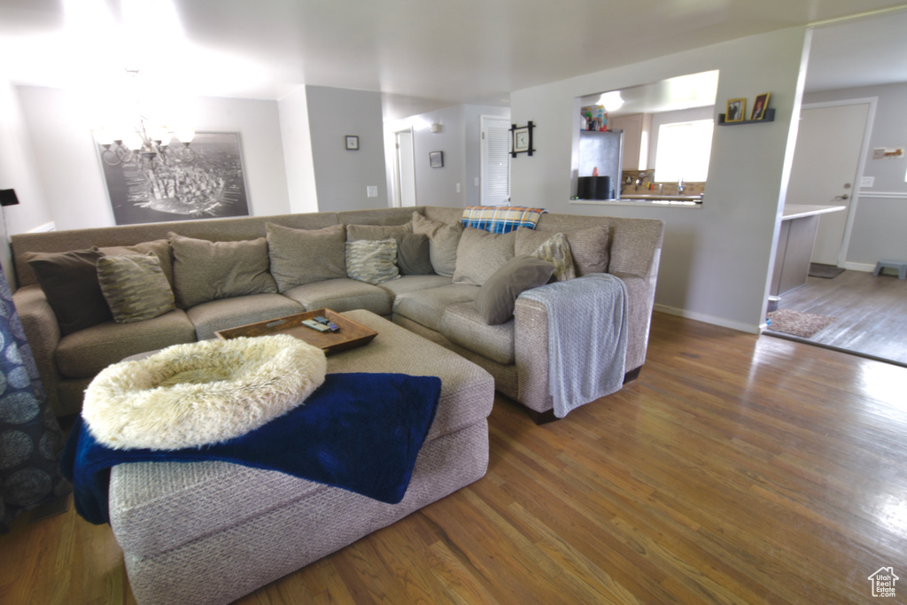 Living area with wood finished floors, a notable chandelier, and baseboards