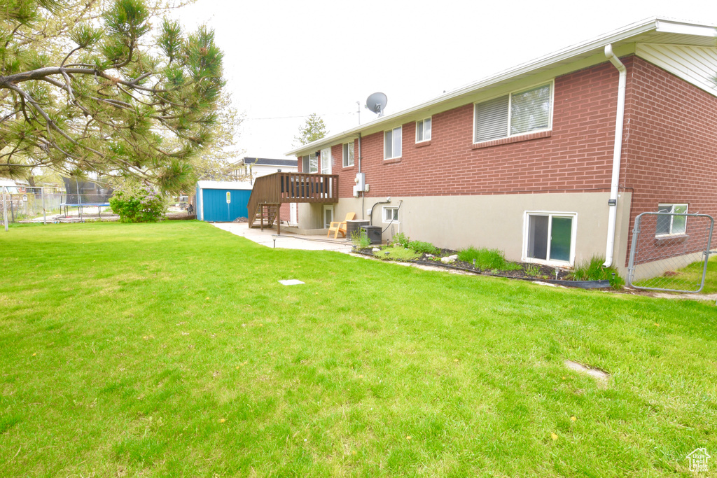 Back of house with brick siding, fence, a shed, and a lawn