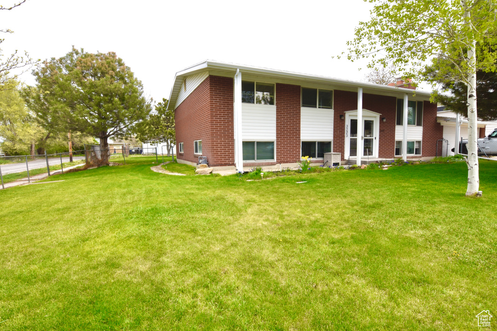Back of property featuring fence, a yard, a chimney, and brick siding
