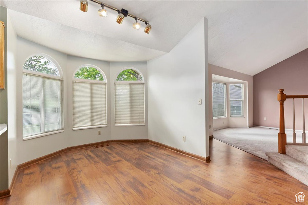 Interior space with plenty of natural light, baseboards, wood finished floors, and vaulted ceiling