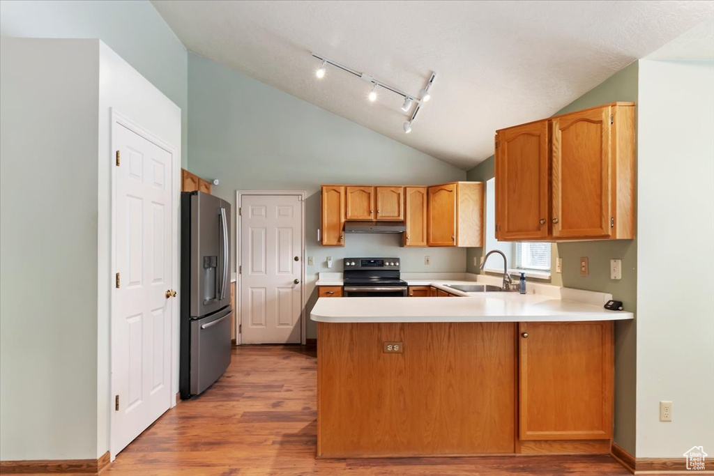 Kitchen with a sink, light countertops, track lighting, a peninsula, and stainless steel appliances