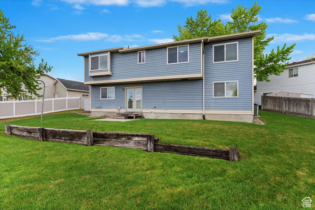 Rear view of property with a fenced backyard, french doors, a yard, and entry steps
