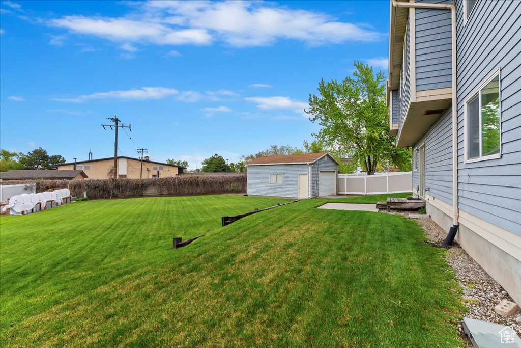 View of yard with fence, an outdoor structure, and a garage