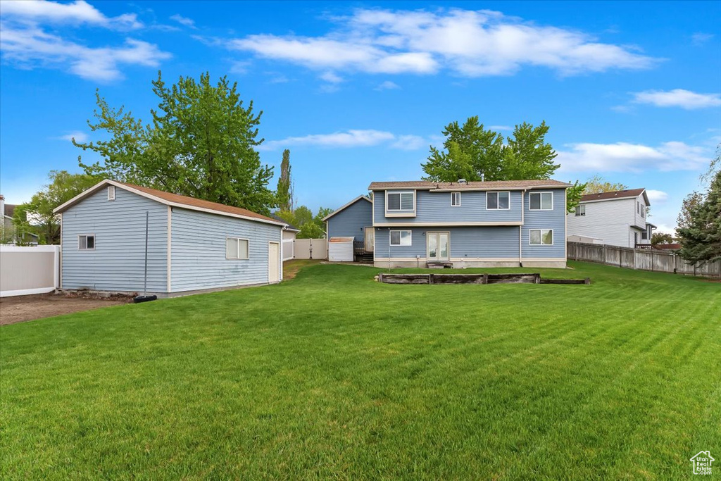 Back of property with a fenced backyard, an outbuilding, and a yard
