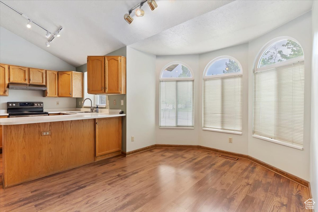 Kitchen with light countertops, track lighting, under cabinet range hood, and stainless steel range with electric cooktop