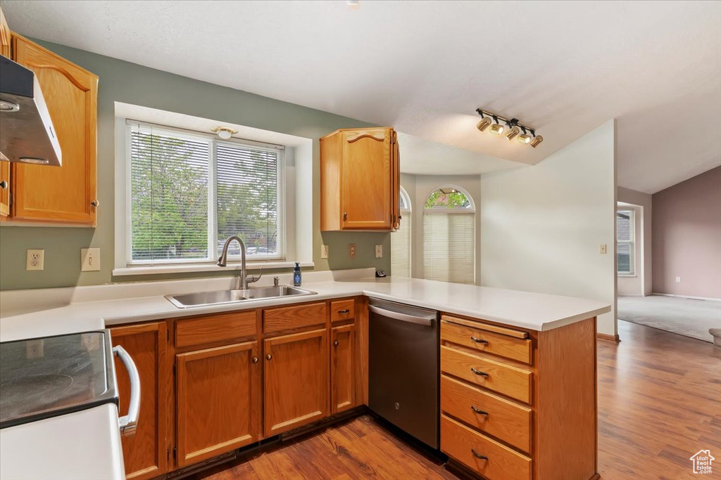 Kitchen with a peninsula, wood finished floors, a sink, dishwasher, and range with electric cooktop