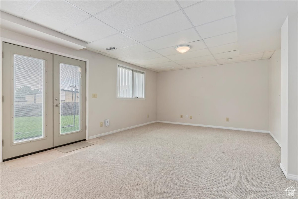 Spare room featuring french doors, carpet, baseboards, a drop ceiling, and visible vents